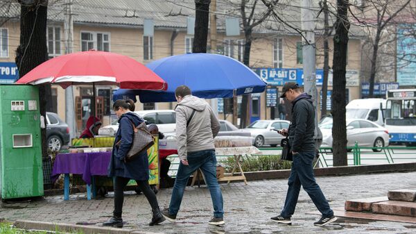 Люди идут по тротуару на одной из улиц Бишкека во время дождя. Архивное фото - Sputnik Кыргызстан