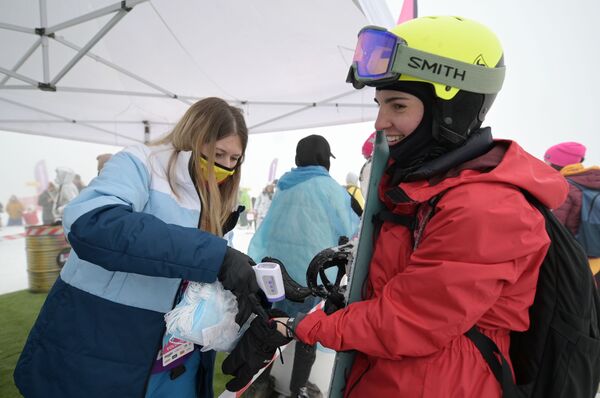 Участнице высокогорного карнавала BoogelWoogel-2021 измеряют температуру перед началом спуска на горнолыжном курорте Роза Хутор в Сочи - Sputnik Кыргызстан