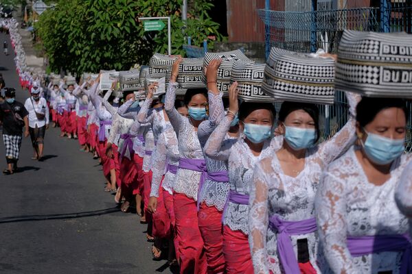 Индонезиянын Бали шаарында өткөн Галунган диний фестивалында кыздар чалынган курмандыктарды алып бара жатышат. - Sputnik Кыргызстан