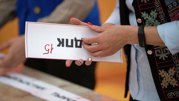 Сотрудница избирательной комиссии держит табличку партии НДПК. Архивное фото - Sputnik Кыргызстан