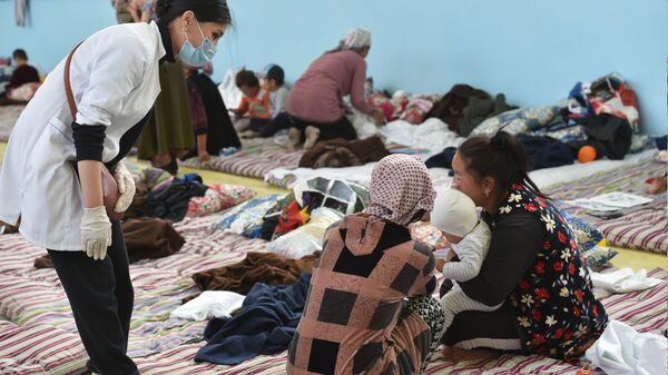 Врач осматривает людей, эвакуированных в город Баткен с конфликтных зон близ границы с Таджикистаном - Sputnik Кыргызстан