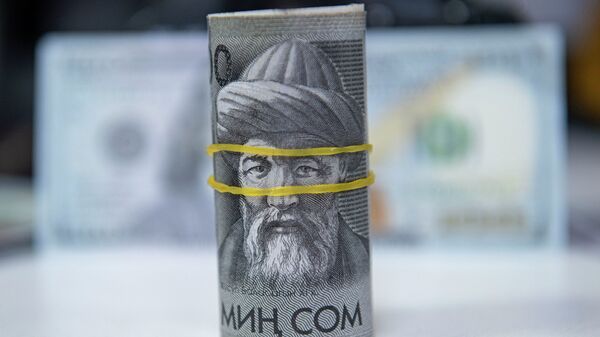 Пачка тысячесомовых купюр на столе на фоне долларовой купюры. Иллюстративное фото - Sputnik Кыргызстан