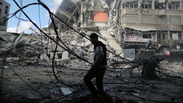 Палестинец проходит мимо разрушенных зданий в результате израильских воздушных ударов - Sputnik Кыргызстан