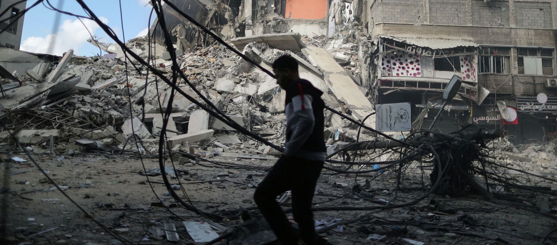 Палестинец проходит мимо разрушенных зданий в результате израильских воздушных ударов - Sputnik Кыргызстан, 1920, 14.05.2021