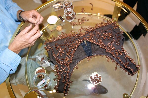 Производитель шоколада Анри Леру пришивает шоколадные жемчужины на бюстье, предназначенное для ношения поверх платья, во время примерки с актрисой Габриель Лазюр в Париже, 2001 год - Sputnik Кыргызстан
