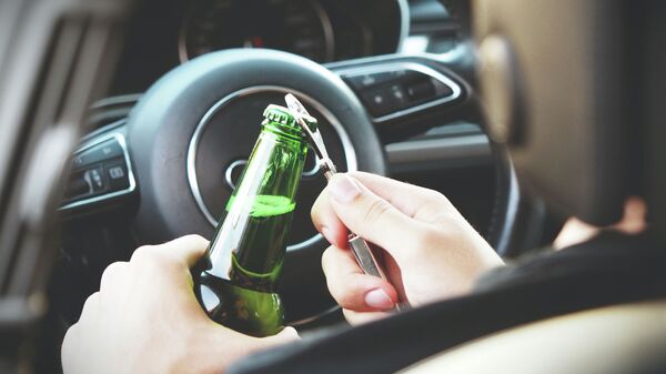 Водитель с алкогольным напитоком за рулем автомобиля. Иллюстративное фото - Sputnik Кыргызстан