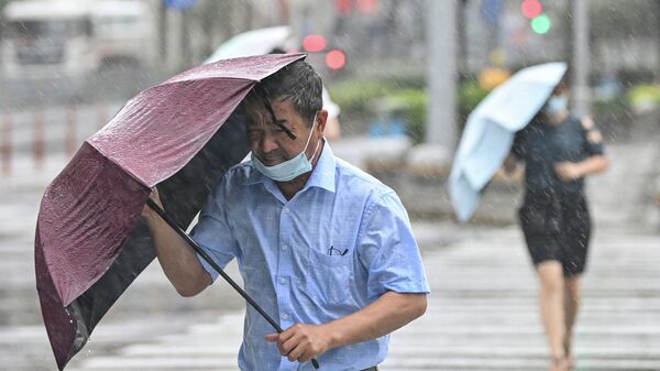 Люди переходят улицу под ветром и дождем во время тайфуна - Sputnik Кыргызстан