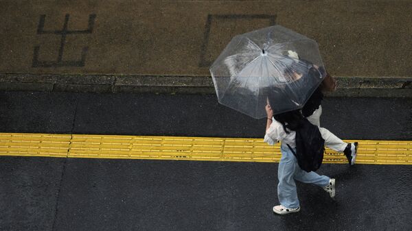 Девушки c зонтом гуляют под дождем. Архивное фото - Sputnik Кыргызстан