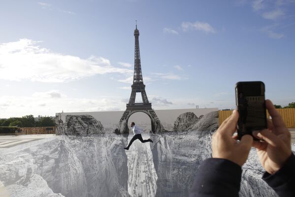 Мужчина позирует на гигантском произведении французского художника JR, установленном на площади Трокадеро перед Эйфелевой башней в Париже - Sputnik Кыргызстан