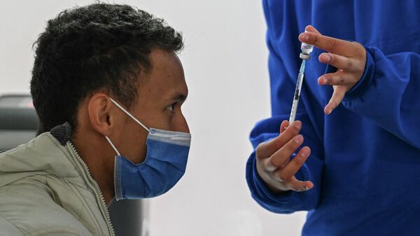 Медицинский работник показывает мужчине ампулу с вакциной против COVID-19. Архивное фото - Sputnik Кыргызстан