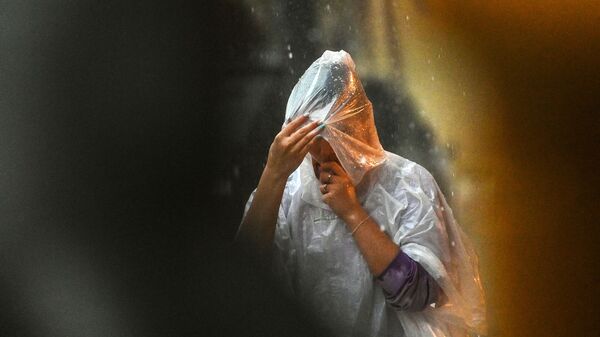 Девушка в дождевике во время дождя. Архивное фото - Sputnik Кыргызстан