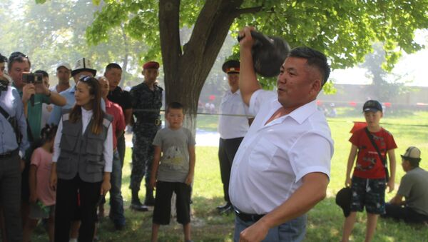 Полномочный представитель президента в Баткенской области Абдикарим Алимбаев поднимает гирю во время праздничных гуляний в честь Дня независимости Кыргызстана - Sputnik Кыргызстан