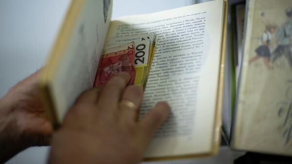 Мужчина прячет деньги в книге. Иллюстративное фото - Sputnik Кыргызстан