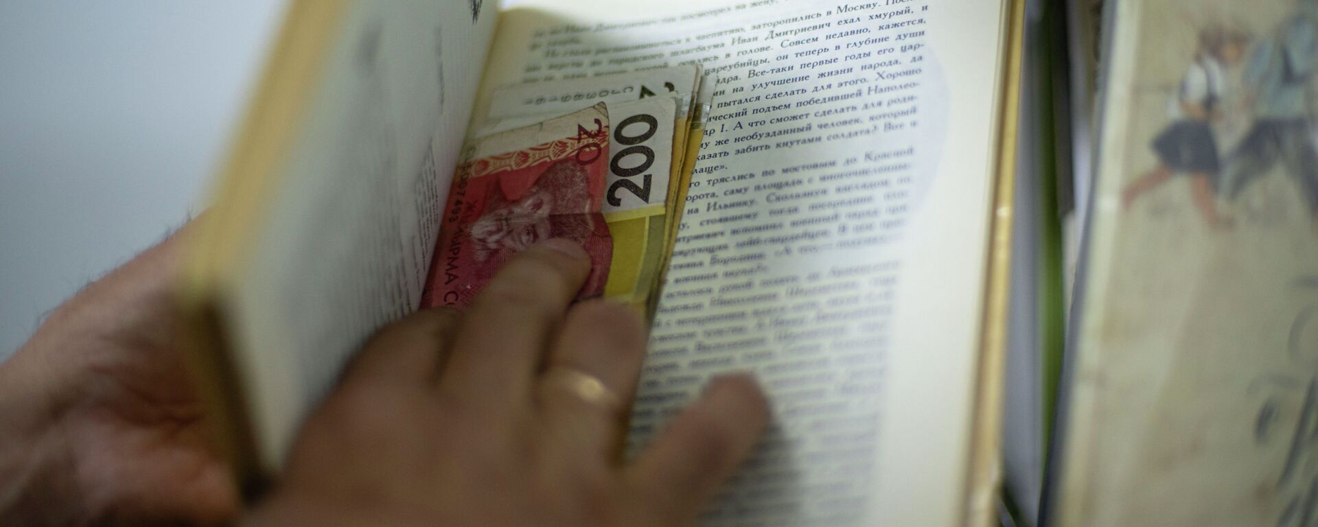 Мужчина прячет деньги в книге. Иллюстративное фото - Sputnik Кыргызстан, 1920, 06.06.2022