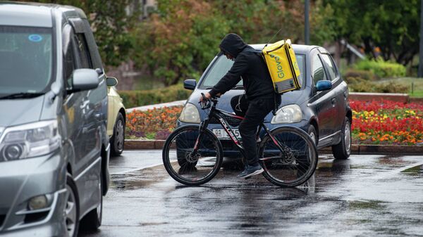 Курьер службы доставки на велосипеде во время дождя в Бишкеке. Архивное фото - Sputnik Кыргызстан