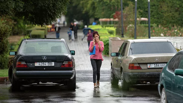 Девушка идет по улице во время кратковременного дождя. Архивное фото  - Sputnik Кыргызстан