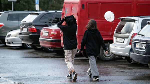 Подростки идут по одной из улиц Бишкека во время кратковременного дождя. Архивное фото - Sputnik Кыргызстан