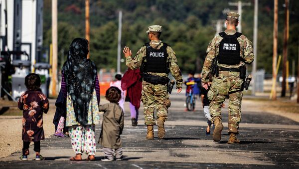 Военная полиция США проходит мимо афганских беженцев на базе армии США в Висконсине - Sputnik Кыргызстан
