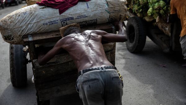 Рабочий толкает загруженную тележку на продуктовом рынке в Порт-о-Пренс (Гаити). Архивное фото - Sputnik Кыргызстан