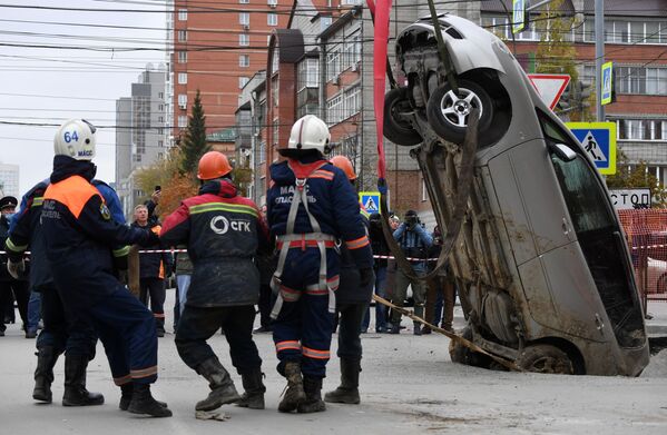 Спасатели в Новосибирске (Россия) вытаскивают автомобиль, провалившийся под асфальт из-за прорыва трубопровода - Sputnik Кыргызстан