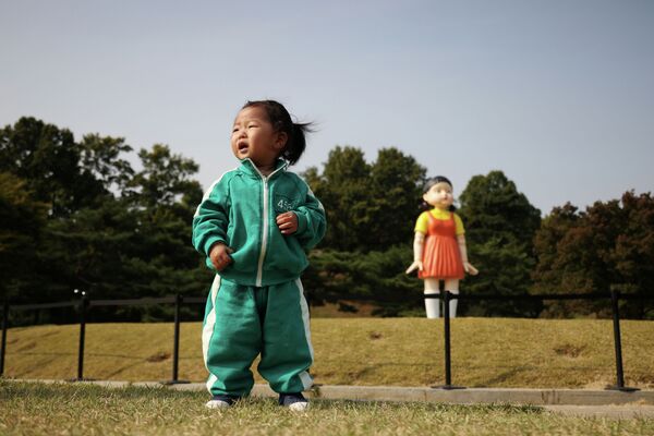 Плачущая девочка на фоне гигантской куклы из сериала Игра в кальмара в сеульском парке.
Южнокорейский сериал Игра в кальмара посмотрели около 132 миллионов человек, что является лучшим результатом для стриминговой платформы Netflix. - Sputnik Кыргызстан
