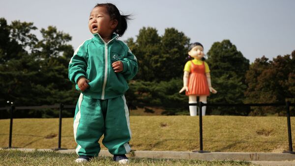 Плачущая девочка на фоне гигантской куклы из сериала Игра в кальмара в сеульском парке. - Sputnik Кыргызстан