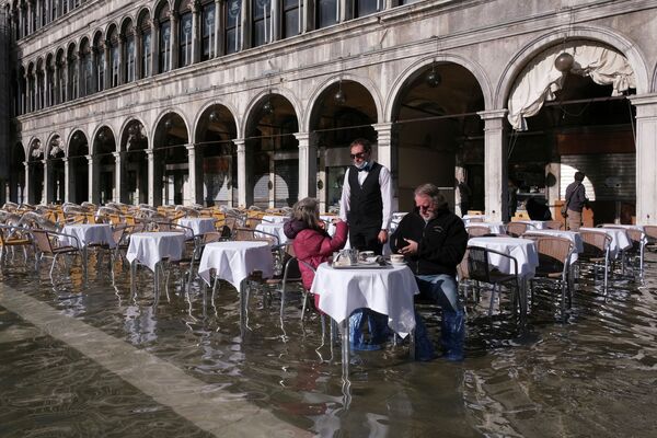 Люди сидят в кафе на затопленной площади Сан-Марко в Венеции (Италия) - Sputnik Кыргызстан