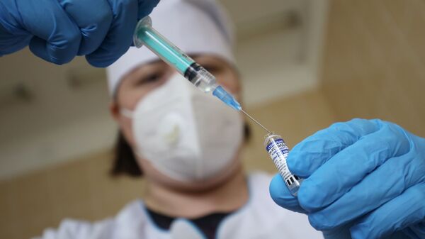 Медицинский сотрудник набирает в шприц препарат от коронавирусной инфекции - Sputnik Кыргызстан