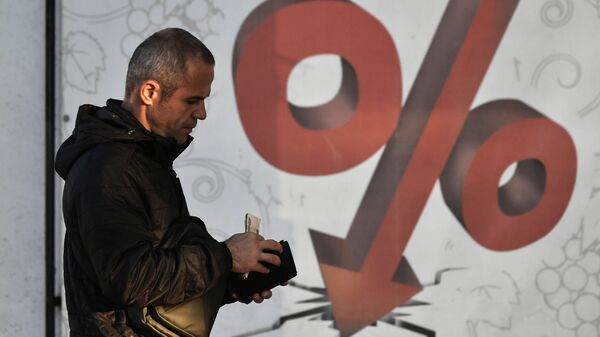 Мужчина проходит мимо плаката с изображением процентов. Архивное фото  - Sputnik Кыргызстан