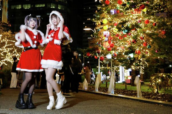 Девушки в костюмах Санта-Клауса фотографируются на фоне рождественской иллюминации в Токио - Sputnik Кыргызстан