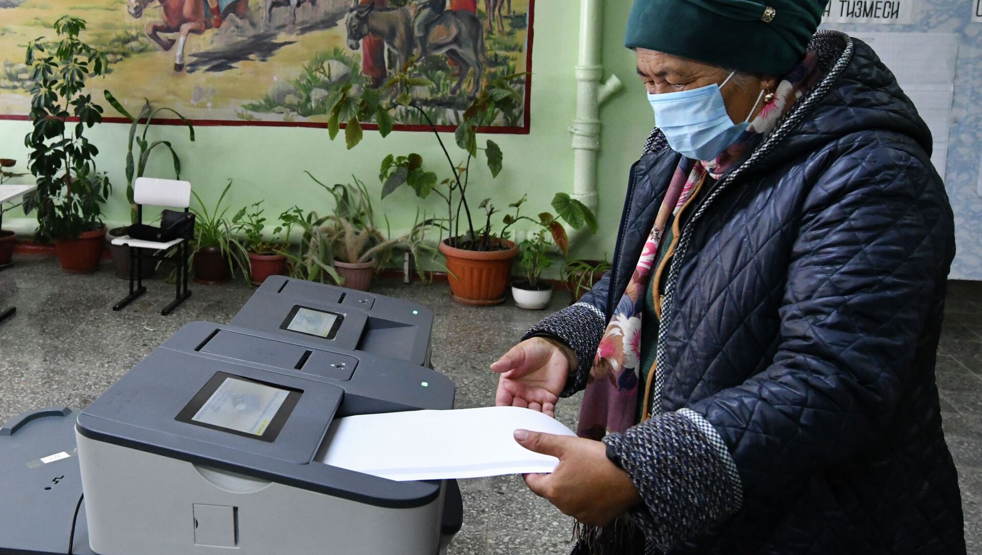 Женщина опускает бюллетень во время парламентских выборов на избирательном участке - Sputnik Кыргызстан, 1920, 30.11.2021
