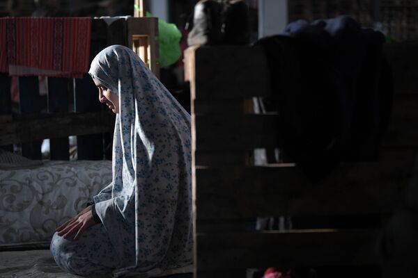 Женщина молится в центре временного содержания мигрантов, оборудованном в пункте пропуска Брузги на белорусско-польской границе - Sputnik Кыргызстан