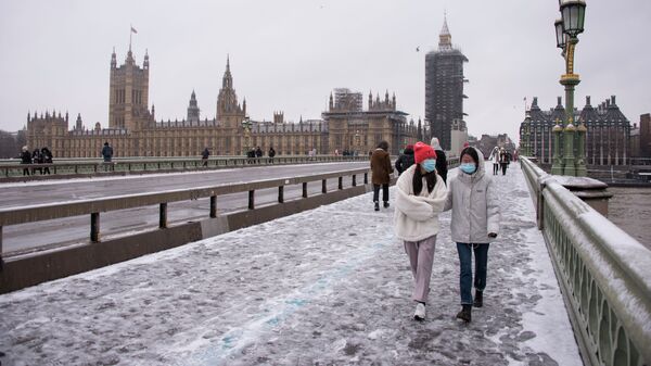 Люди в масках идут по Вестминстерскому мосту во время снегопада в Лондоне - Sputnik Кыргызстан