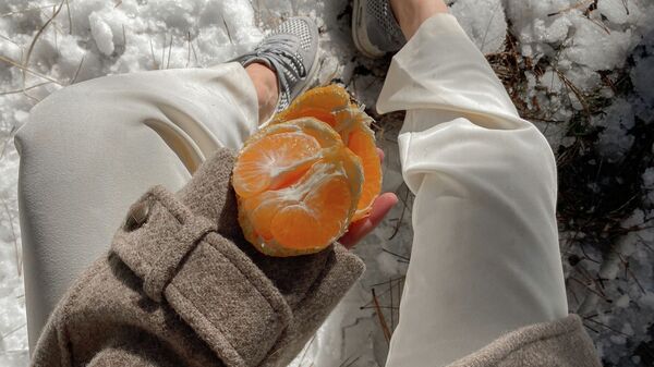 Девушка с мандарином в руках. Иллюстративное фото - Sputnik Кыргызстан