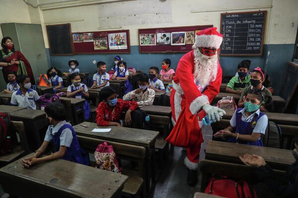 Мужчина в костюме Санта-Клауса дезинфицирует руки школьникам в Мумбаи (Индия) - Sputnik Кыргызстан