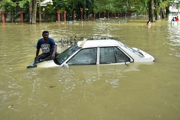 Житель Малайзии ждет эвакуации на крыше автомобиля. Из-за продолжающихся проливных дождей несколько районов страны фактически ушли под воду. - Sputnik Кыргызстан
