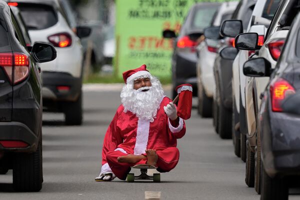 Мужчина с инвалидностью в костюме Санта-Клауса собирает милостыню, катаясь на скейтборде в Бразилиа - Sputnik Кыргызстан
