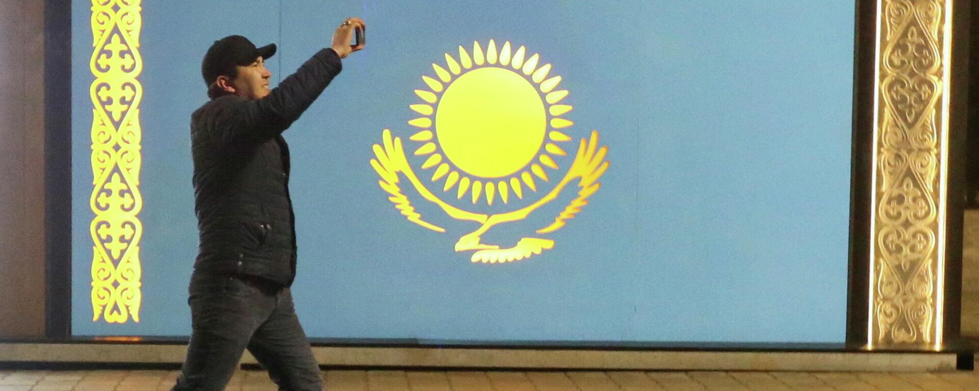 Мужчина проходит мимо флага Казахстана во время акции протеста против повышения цен сжиженного газа в Алматы, Казахстан. 5 января 2022 года - Sputnik Кыргызстан, 1920, 05.01.2022