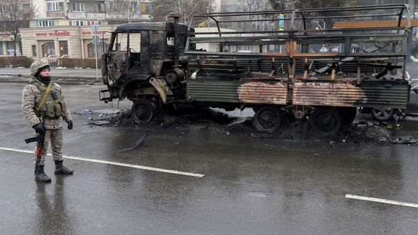 Сотрудник правоохранительных органов Казахстана возле сгоревшего грузовика в Алматы - Sputnik Кыргызстан