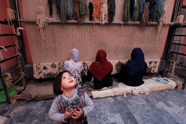 Пятилетняя девочка играет, пока ее мама работает в домашней мастерской по изготовлению ковров в Пешаваре (Пакистан) - Sputnik Кыргызстан