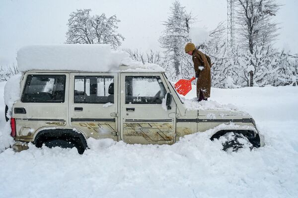 Кабелтең жааган кар. Бала автоунааны басып калган карды күрөп жатат. Кашмир (Индия) - Sputnik Кыргызстан