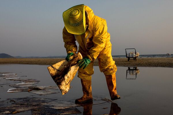 Рабочий очищает от нефти пляж Мае Рам Фуенг в Таиланде. Утечка нефти из подводного трубопровода произошла в Сиамском заливе Южно-Китайского моря. - Sputnik Кыргызстан