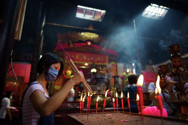 Девушка ставит свечу в храме в Куала-Лумпуре (Малайзия) в день лунного Нового года - Sputnik Кыргызстан