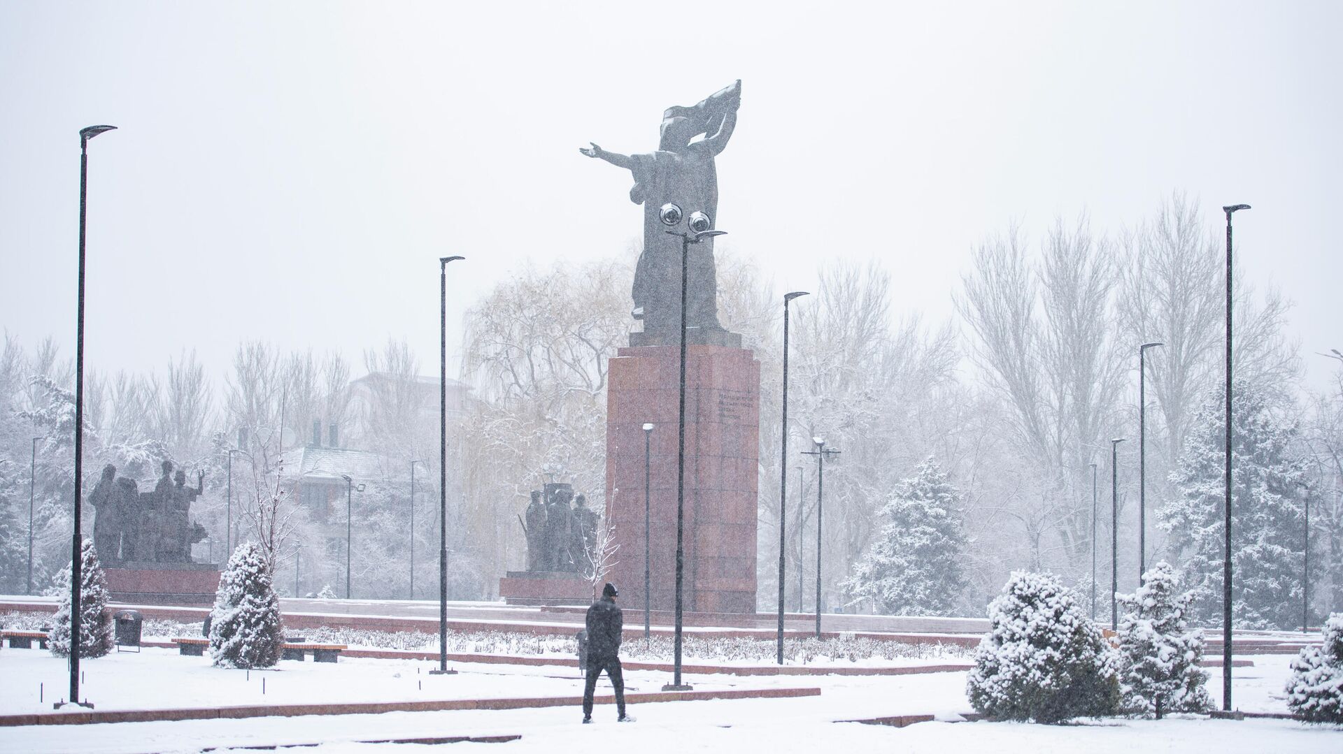 Мужчина идет возле памятника Уркуе Салиевой во время снегопада в Бишкеке. Архивное фото - Sputnik Кыргызстан, 1920, 07.11.2022