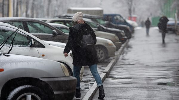 Девушка переходит дорогу, где припаркованы автомобили во время снегопада. Архивное фото - Sputnik Кыргызстан