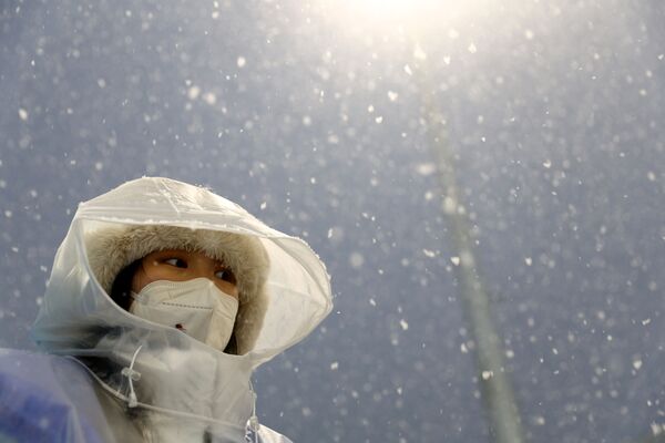 Олимпийская чиновница во время снегопада наблюдает за атлетами на гонке преследования на 10 километров - Sputnik Кыргызстан
