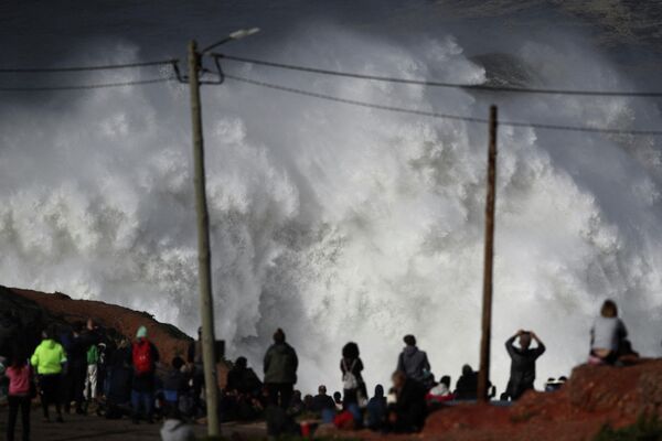 Люди наблюдают за волнами на побережье в Назаре (Португалия) - Sputnik Кыргызстан