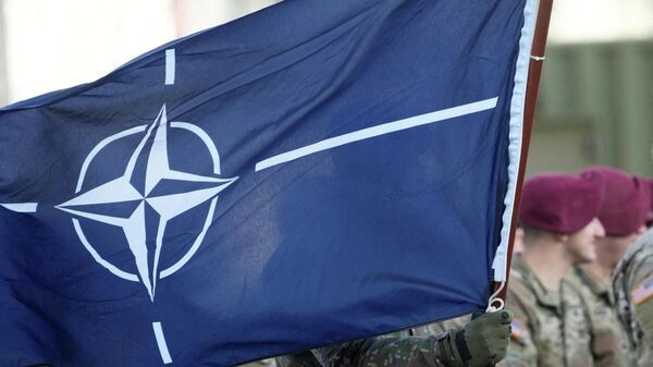 Флаг НАТО во время церемонии прибытия американских войск на военную базу в Латвии - Sputnik Кыргызстан