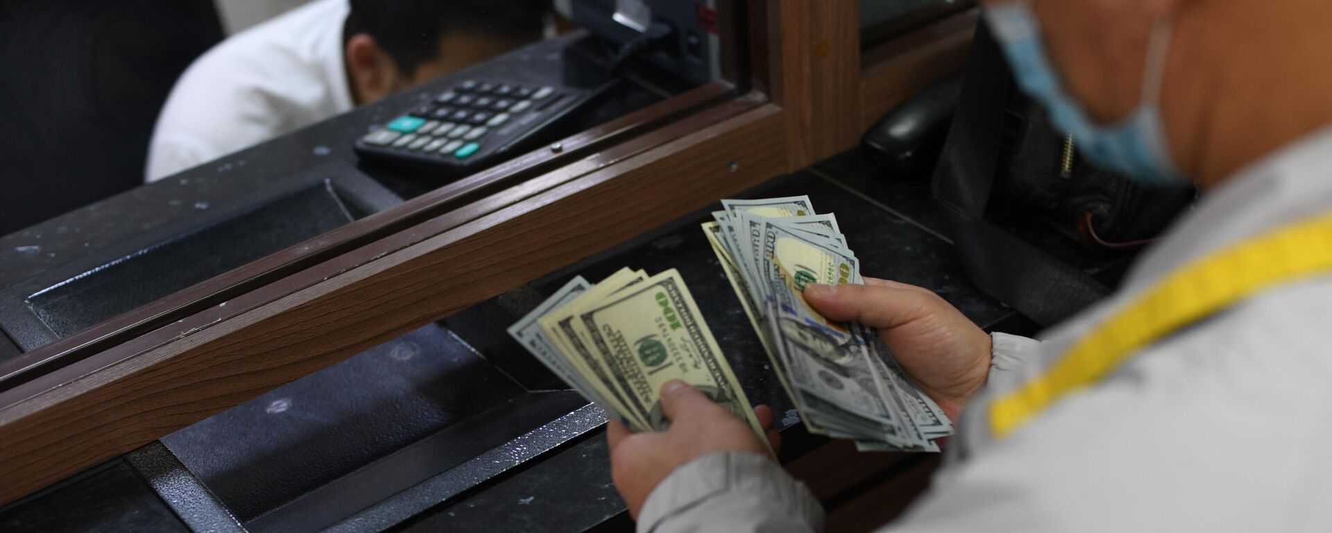Мужчина пересчитывает доллары США в обменном бюро в Бишкеке - Sputnik Кыргызстан, 1920, 09.03.2022