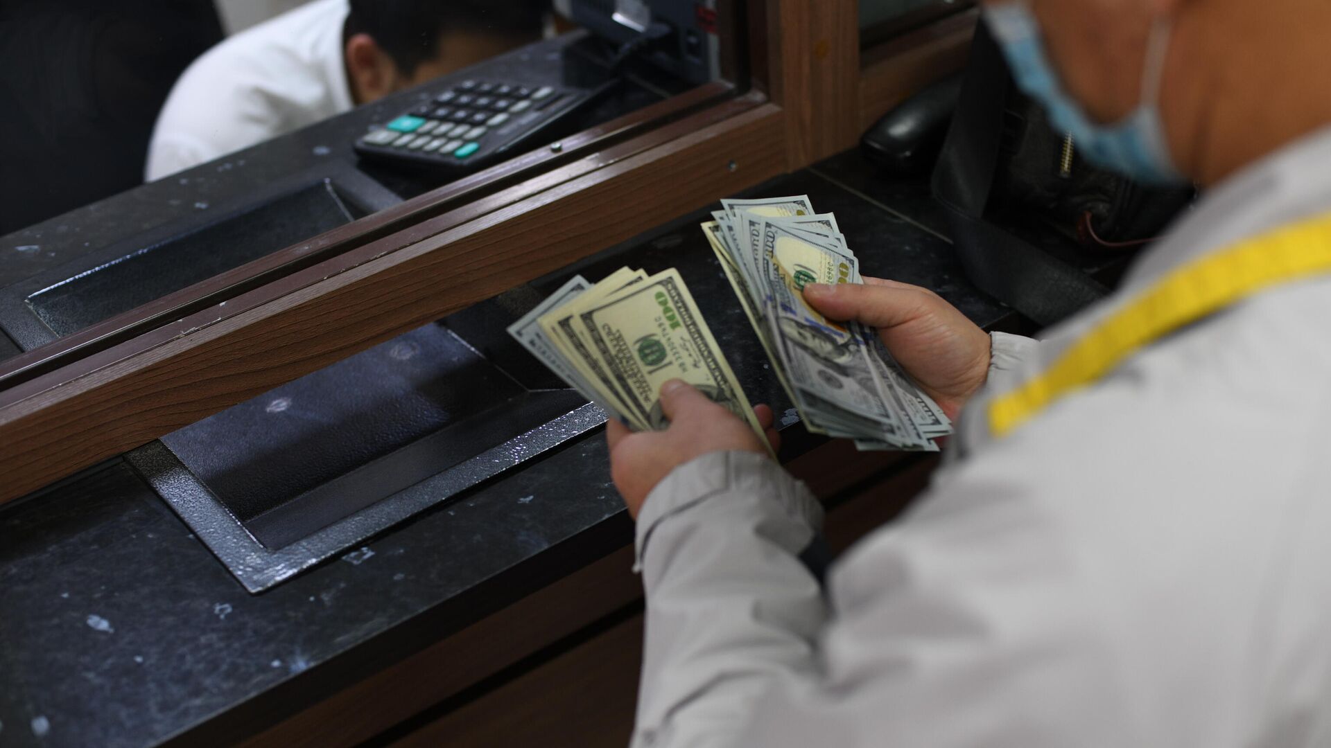 Мужчина в обменном бюро считает доллары США. Архивное фото - Sputnik Кыргызстан, 1920, 31.05.2022